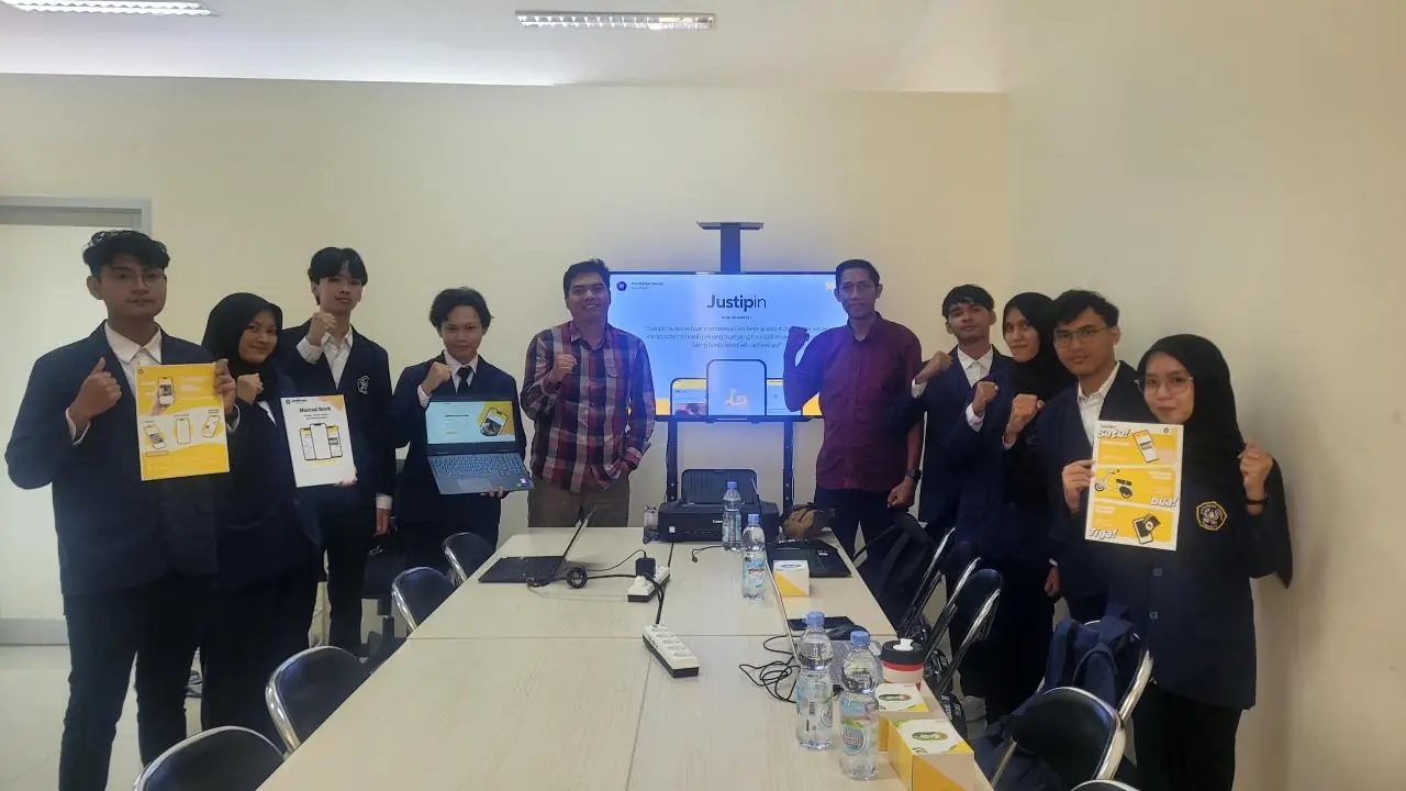 The Justipin team at the final presentation, holding printed flyers, the user manual and a laptop running the app.