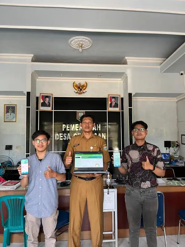 Handover at the Gedangan village office: the two developers and a village official holding phones and a laptop running the system.