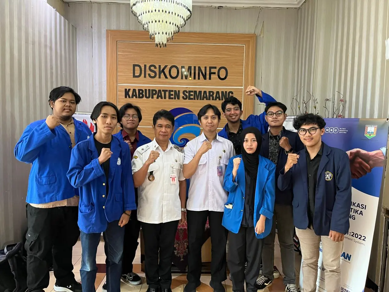 The internship team with two Diskominfo Kabupaten Semarang staff members in front of the Diskominfo sign.